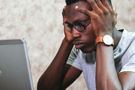 En kille ser bekymrad ut framför datorn.